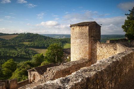 A beautiful shot of a stone tower and tree-covered fields in Puycelci, Franceの写真素材