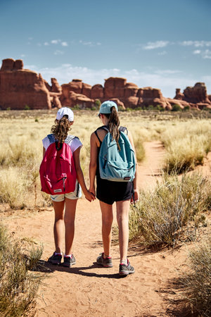 A beautiful scenery of two girls walking in a canyon landscape in Arches National Park, Utah - USA