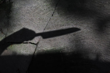 A high angle shot of a shadow of human hand holding a knife- murder concept