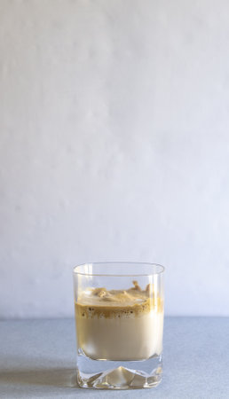 A vertical selective focus shot of a glass of coffee on a blue surface