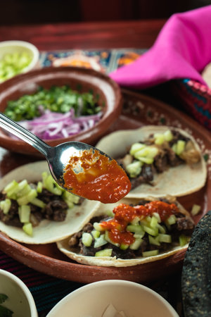 A vertical shot of tortillas with meat seen through tomato sauce spoonの写真素材