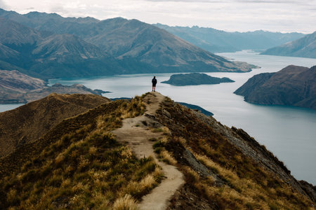 A male standing on a top of the mountain range with a sea in the background, Roys Peak Glendhuの写真素材