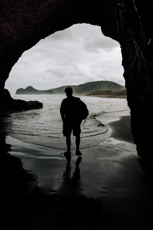 A vertical shot of a young male on Cathedral Cove, New Zealandの写真素材