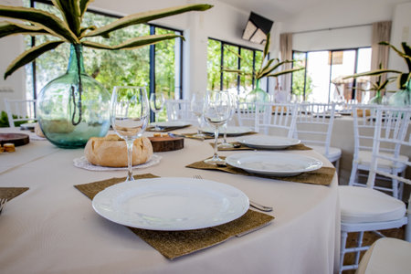 A closeup shot of white plates and wine glasses on a round restaurant table