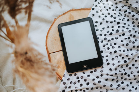 A Ebook Reader on a wooden disc and black and white dotted fabricの写真素材