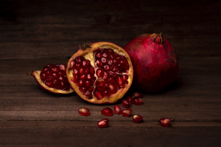 A closeup of pomegranates on a wooden table with a dark blurry backgroundの写真素材