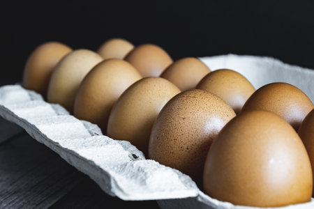 Closeup of orange eggs placed in a cardboard egg cup. Gastronomic photo