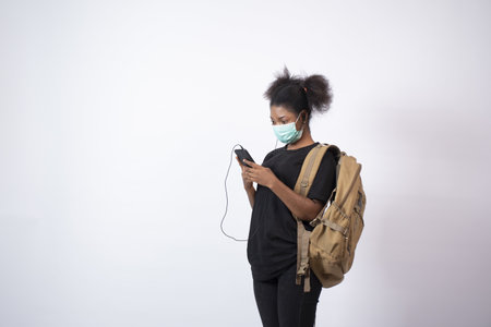 A young African female wearing a face mask using her mobile phone - the new normal concept