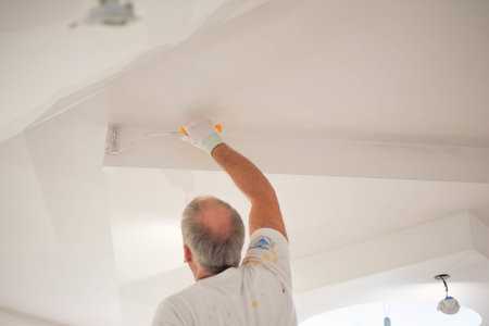 A back view of a handyman painting a wall with a paintbrushの写真素材