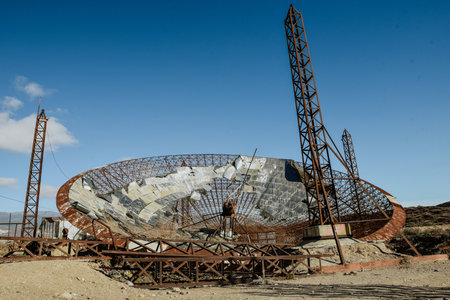 An old, abandoned and rusty parabola antenna with three towersの写真素材