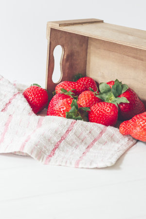 A vertical shot of fresh and delicious strawberries in a wooden box on a napkinの写真素材