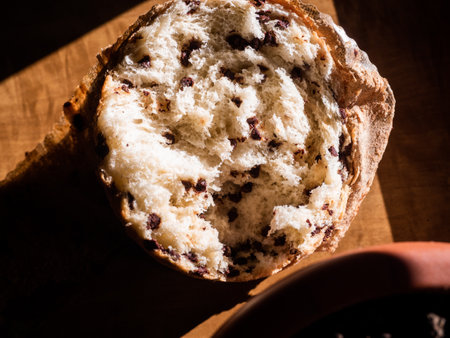 A top view of a delicious bun with raisins on a wooden table under the lights