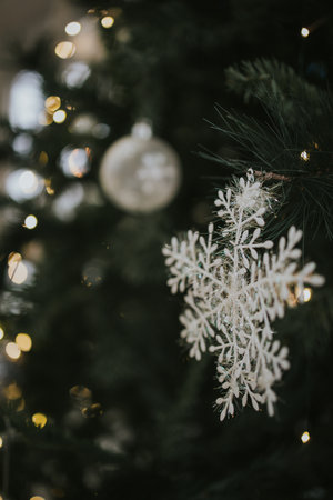 A vertical shot of a snowflake and beautiful silver ornaments on a Christmas tree, indoors