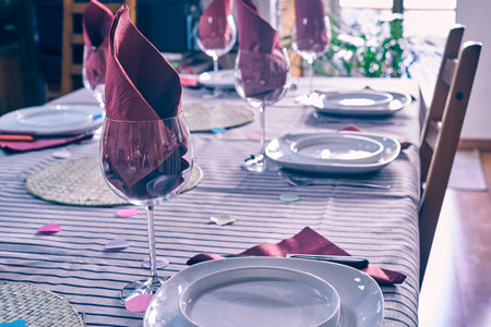 A table with plates, wine glasses and purple napkins - preparation for the party, celebrationの写真素材