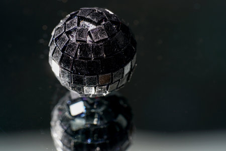 A closeup of a small handmade disco ball against a dark blurry backgroundの写真素材
