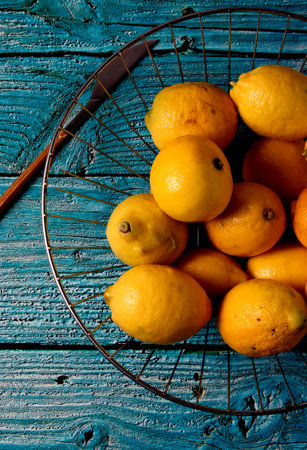 A vertical shot of fresh lemons on a plate and on a blue wooden tableの写真素材