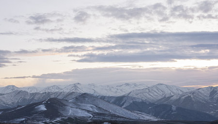 An overlooking view of mountains covered with snow with beautiful scenery of sunset in a cloudy sky...
