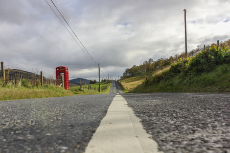 road through a rural area of Scotland, you can see in the distance a red telephone box