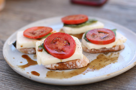 A closeup shot of bread with cheese and tomato on a white plate