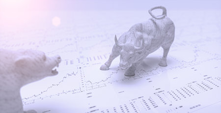 A greyscale shot of a bear and bull on top of the stock chart paper
