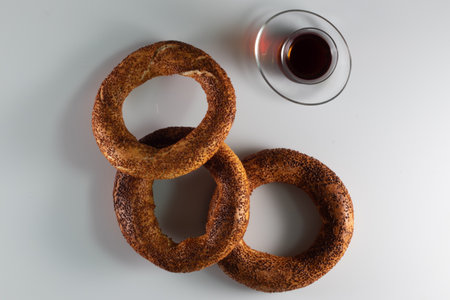 A high angle shot of freshly-baked sweet simits and a cup of tea on a white surface
