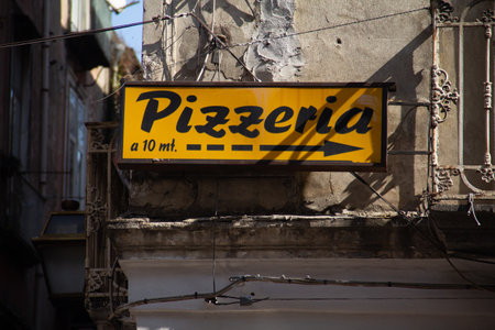 A yellow banner showing the direction to pizzeria attached to the old buildingのeditorial素材