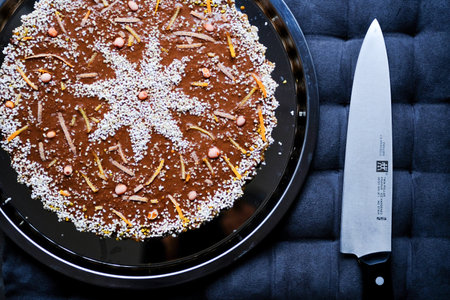 raw vegan tart with cashew and chocolate on a silver plate with a knife next to itのeditorial素材