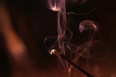 A closeup shot of a burning incense stick on a dark backgroundの写真素材
