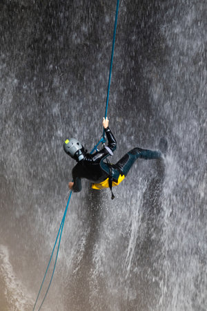 A person doing canyoning sport on Vanatarile Ponorului waterfall in Transylvania, Romaniaの写真素材
