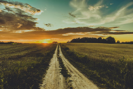A majestic sunset view over a landscape with an unpaved road disappearing into the horizon