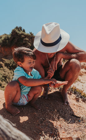 The father and his son happily playing on the sandy beachの写真素材