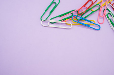 A closeup shot of colorful paper clips on a purple background