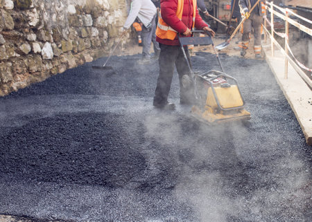 A lot of construction workers working and making a mini-roller asphalt roadの写真素材