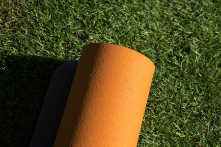A high angle shot of an orange yoga mat on the grass under the sunlightの写真素材