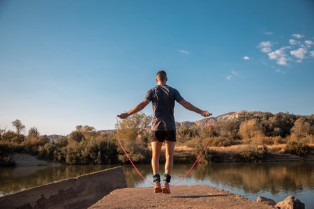 A male training with a jumping-rope next to the riverの写真素材