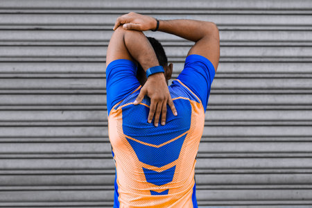 A back view of a young hispanic male doing arm exercises in front of a garage doorの写真素材