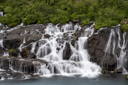 The Hraunfossar waterfalls surrounded by greenery at daytime in Icelandの写真素材