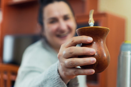 A middle-aged happy woman offering the traditional Argentina yerba mate tea in a wooden bowlの写真素材