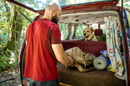 A Caucasian male with his Golden Retriever preparing for trekking in a forestの写真素材