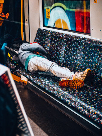 A vertical shot of a male sleeping on the seat inside an empty trainの写真素材