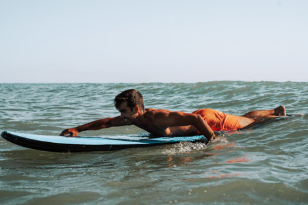 A male surfer surfing on small wavesの写真素材