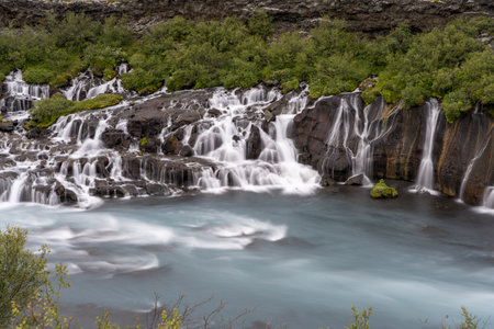 The Hraunfossar waterfalls surrounded by greenery at daytime in Icelandの写真素材
