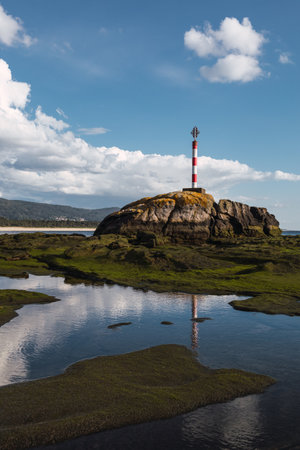 A vertical shot of a lighthouse on a rocky shoreの写真素材