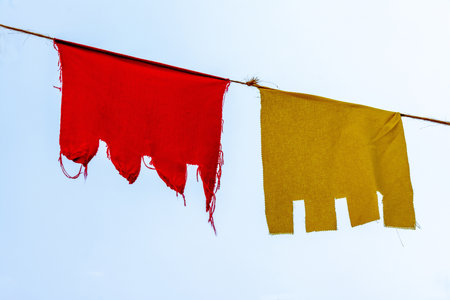 A closeup shot of colored cloth hanging in a rope with a clear sky backgroundの写真素材