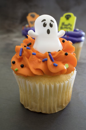 A vertical shot of Halloween cupcakes with colorful spooky toppings on the table