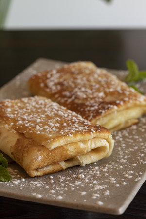 A vertical closeup shot of pancake rolls with powdered sugar