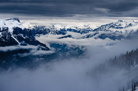 The snowy peaks of rocky mountains under the cloudy sky - perfect for background