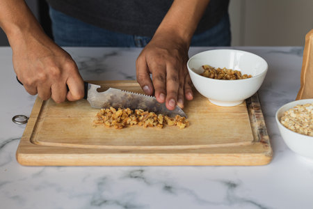 A closeup shot of a chef slicing almonds on a kitchen board to make cookies