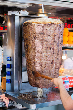 A vertical shot of a person preparing meat for Doner Kebab under the lightsの写真素材