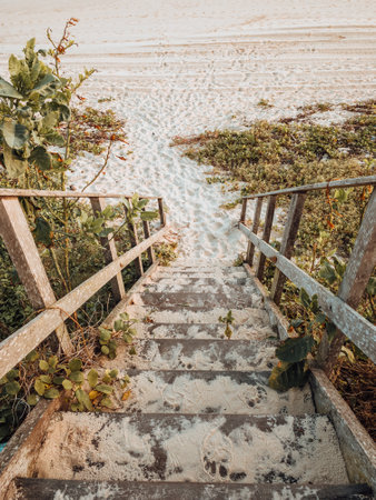 A beautiful landscape shot of the stairs to the beach with golden sunset colors